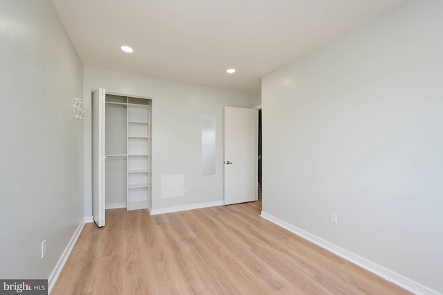 unfurnished bedroom with light wood-style flooring, baseboards, recessed lighting, and a closet