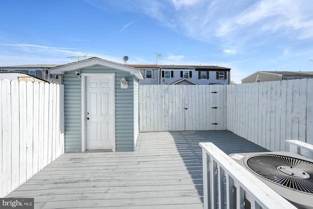 wooden terrace featuring a fenced backyard, an outbuilding, and a storage shed