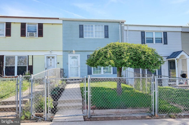 multi unit property featuring a gate, cooling unit, a front yard, and a fenced front yard