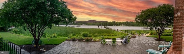 712 Riverside Pines Ct, Salisbury, MD 21801 - patio terrace at dusk featuring a patio area, a water view, and a lawn