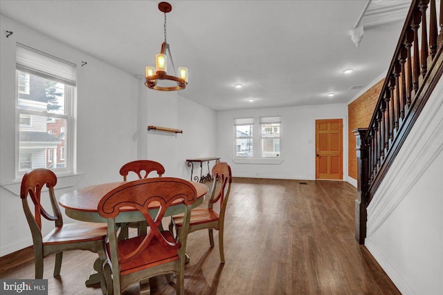 dining space featuring visible vents, baseboards, an inviting chandelier, wood finished floors, and stairs