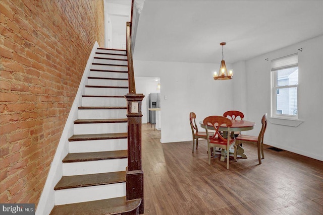 dining area featuring visible vents, wood finished floors, stairs, baseboards, and a notable chandelier
