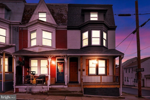 view of front of house featuring brick siding, a porch, and a shingled roof