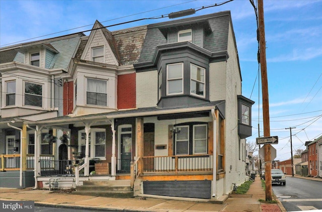 view of front facade with brick siding and covered porch