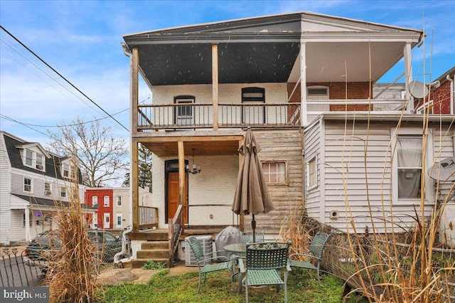back of property with central AC unit and a balcony