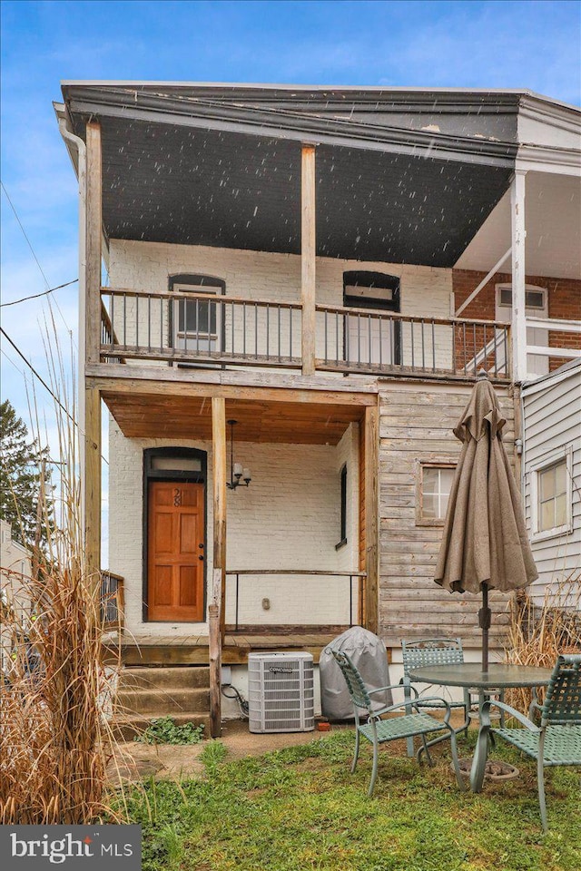 rear view of house with cooling unit and a balcony