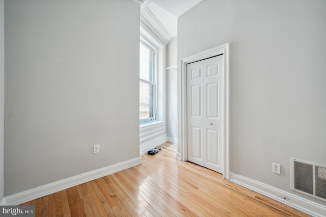unfurnished bedroom with baseboards, a closet, wood-type flooring, and visible vents