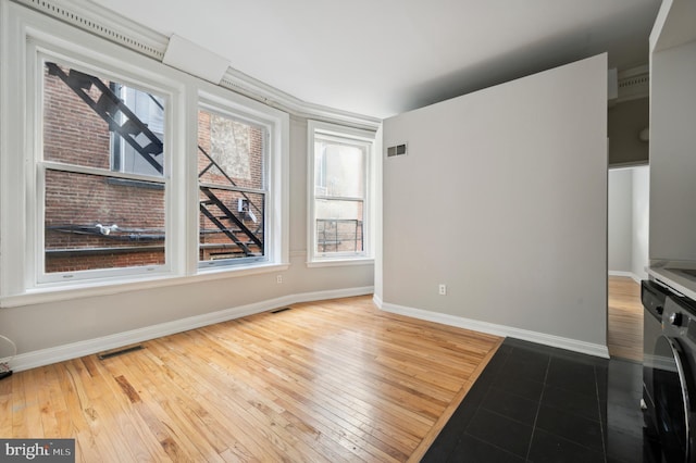 unfurnished living room featuring washer / clothes dryer, baseboards, wood-type flooring, and visible vents