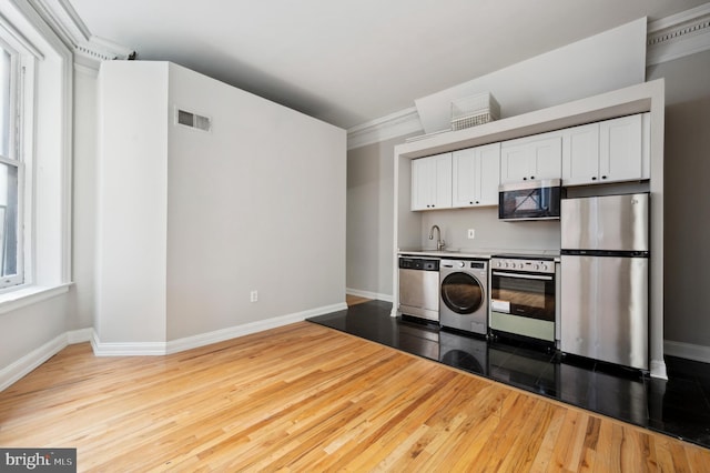 kitchen featuring washer / clothes dryer, white cabinetry, visible vents, appliances with stainless steel finishes, and wood finished floors