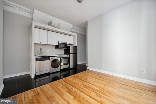 kitchen featuring white cabinetry, baseboards, washer / dryer, and stainless steel appliances