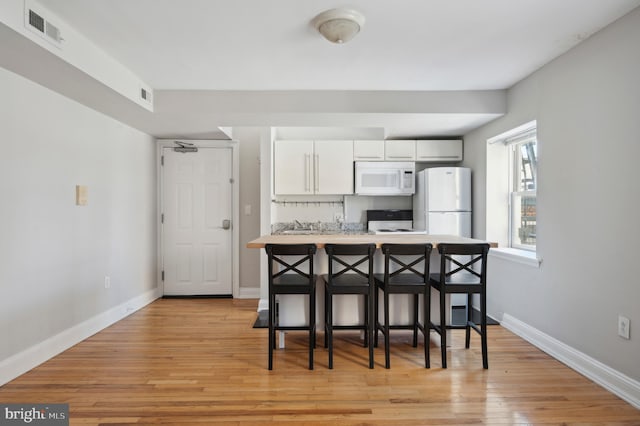 kitchen featuring visible vents, light countertops, light wood-type flooring, white appliances, and white cabinetry