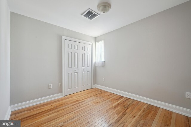 unfurnished bedroom featuring visible vents, baseboards, a closet, and light wood-style floors