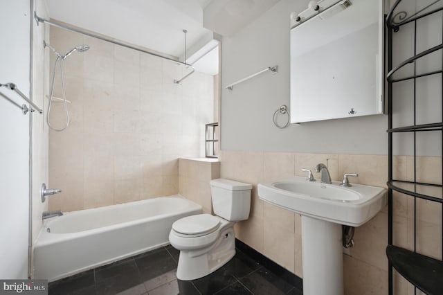 full bathroom featuring toilet, tile walls, a wainscoted wall,  shower combination, and tile patterned floors