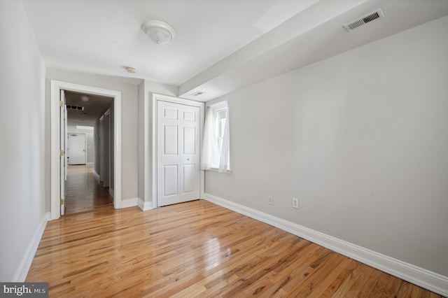unfurnished bedroom with a closet, visible vents, light wood-type flooring, and baseboards