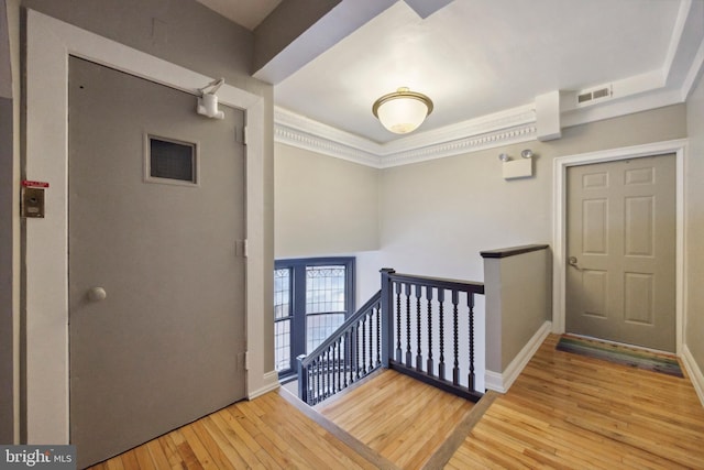 entrance foyer with visible vents, baseboards, hardwood / wood-style floors, and ornamental molding