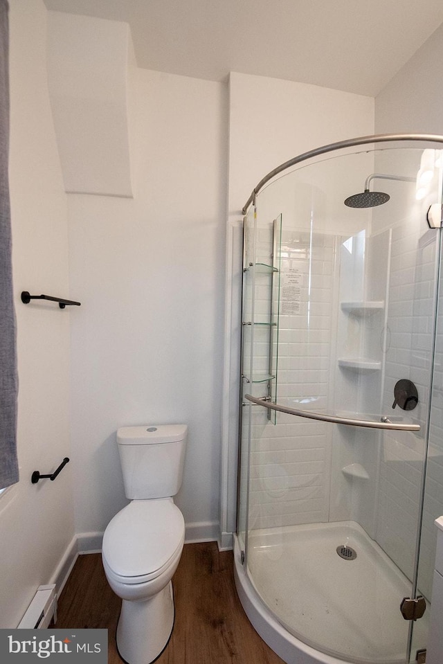 full bathroom with a shower stall, wood finished floors, a baseboard heating unit, and toilet