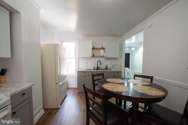 kitchen with dark wood-style floors, light countertops, freestanding refrigerator, open shelves, and a sink