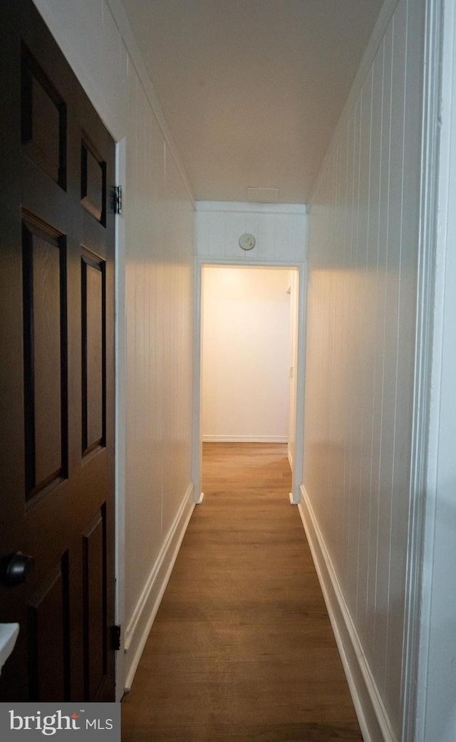 corridor with crown molding, wood finished floors, and baseboards