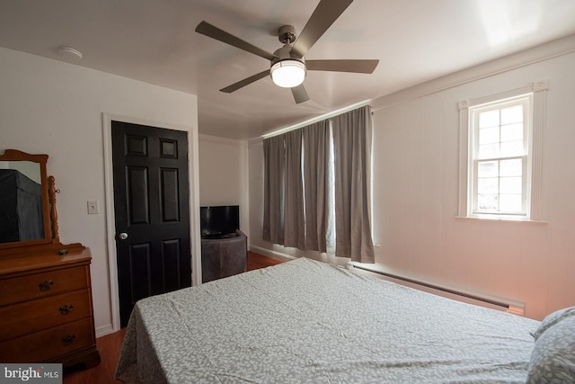 bedroom with dark wood-style flooring, a baseboard heating unit, and a ceiling fan