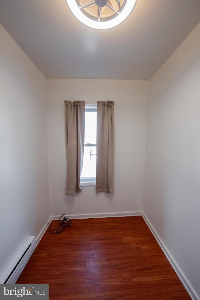 spare room with baseboard heating, baseboards, and wood finished floors