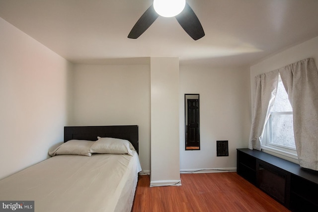 bedroom with ceiling fan, wood finished floors, and baseboards