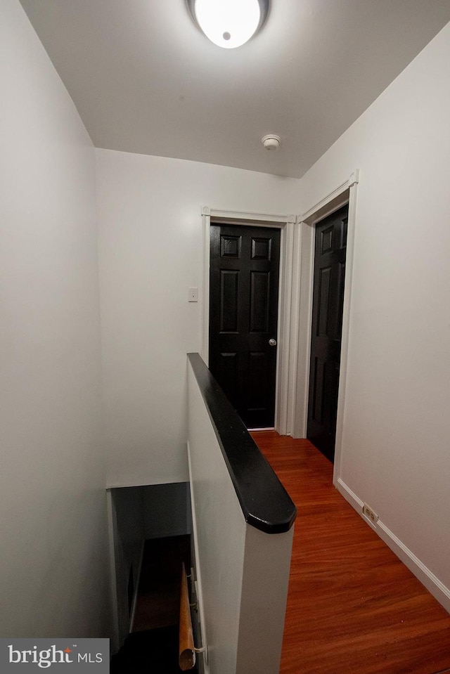 hall featuring baseboards, an upstairs landing, and wood finished floors