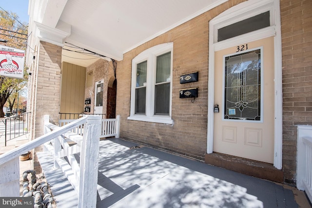 view of exterior entry featuring brick siding and a porch