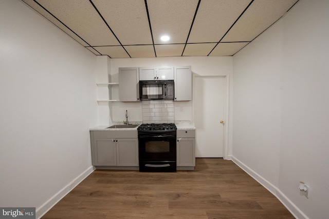 kitchen with baseboards, open shelves, a sink, black appliances, and decorative backsplash