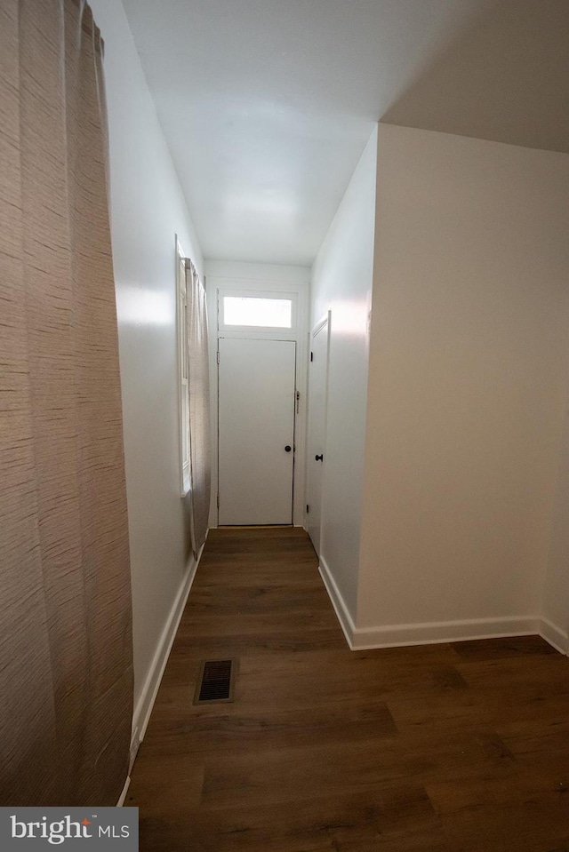 hall featuring wood finished floors, baseboards, and visible vents