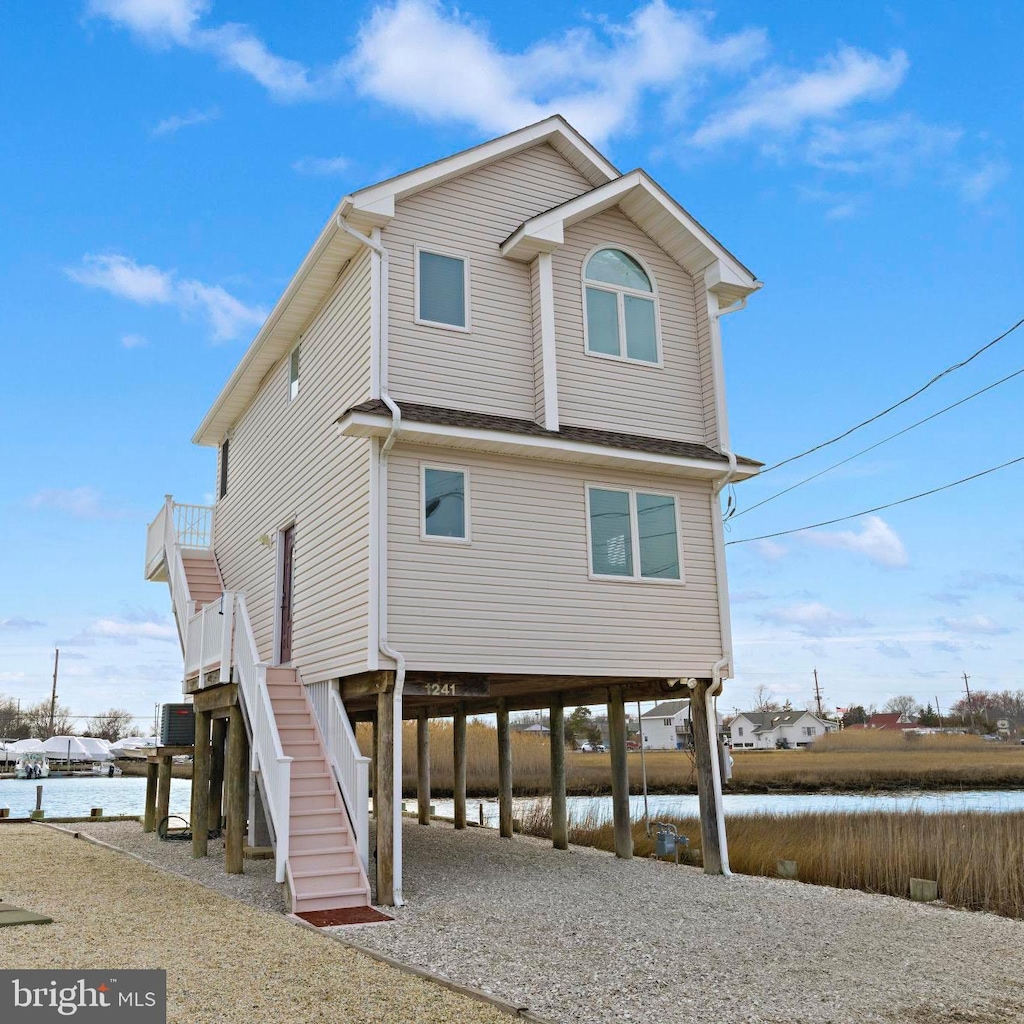 exterior space with a carport, driveway, a water view, and stairs
