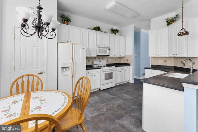kitchen featuring an inviting chandelier, white appliances, backsplash, dark countertops, and a sink