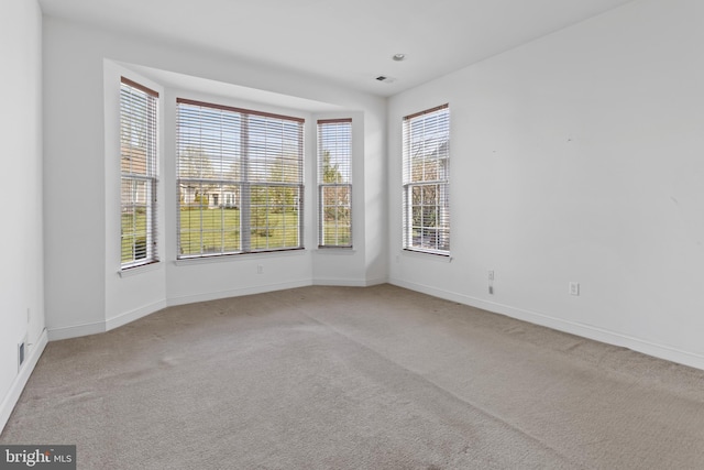 empty room featuring visible vents, baseboards, and carpet