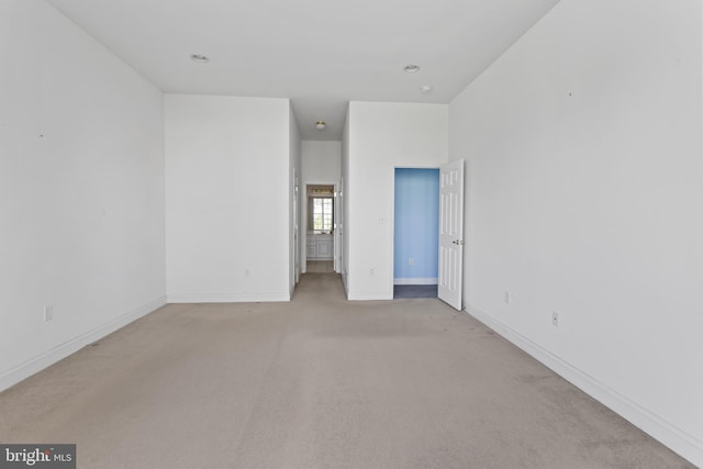 unfurnished room with light colored carpet and baseboards