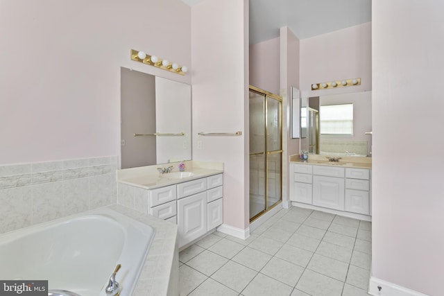 bathroom featuring a bath, a stall shower, two vanities, and a sink