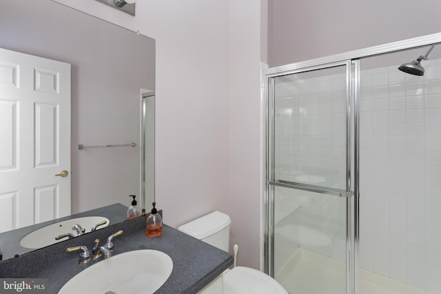 bathroom featuring toilet, vanity, and a stall shower