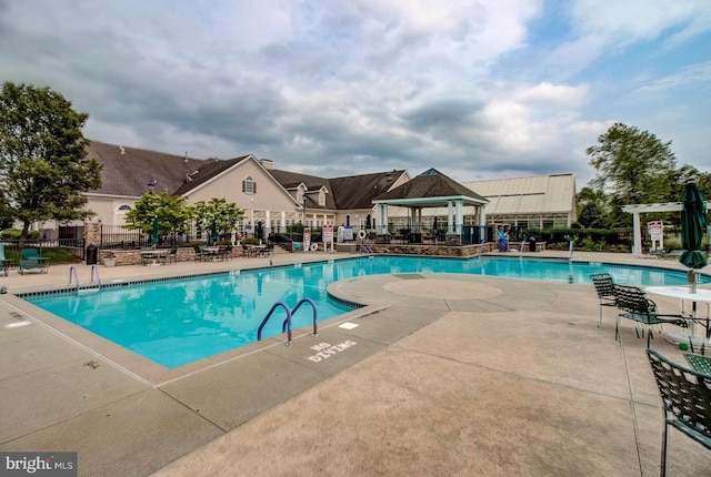 community pool with a gazebo, a patio area, and fence