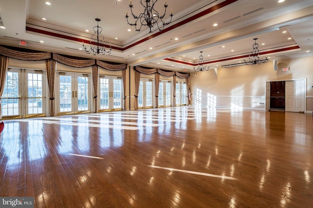 interior space featuring ornamental molding, a chandelier, french doors, a raised ceiling, and wood-type flooring