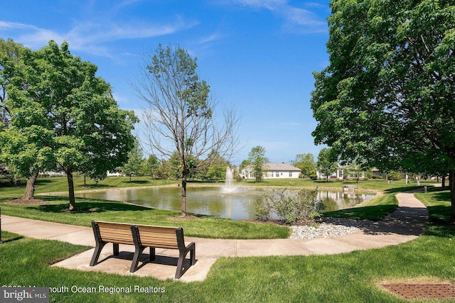view of property's community with a lawn and a water view