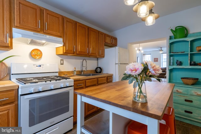 kitchen with under cabinet range hood, wood counters, white appliances, and a sink