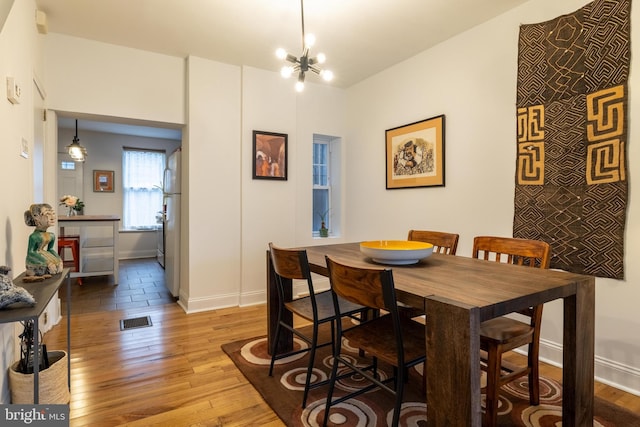 dining room featuring visible vents, baseboards, a notable chandelier, and hardwood / wood-style flooring