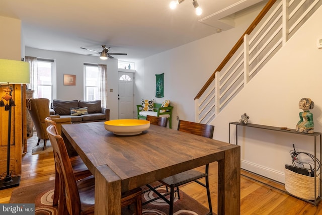 dining room featuring stairway, baseboards, a ceiling fan, and wood finished floors