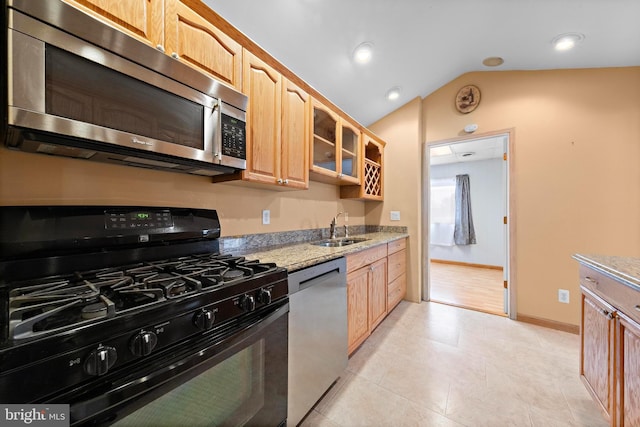 kitchen with glass insert cabinets, light stone countertops, appliances with stainless steel finishes, a sink, and lofted ceiling