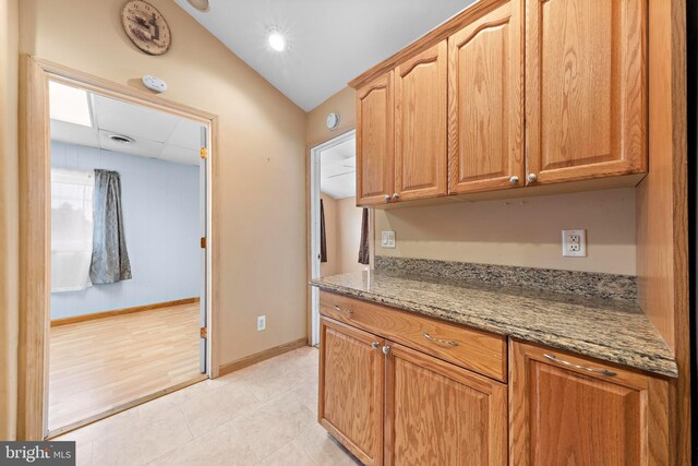 kitchen featuring visible vents, baseboards, a paneled ceiling, light stone countertops, and light tile patterned flooring