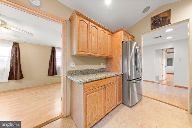 kitchen with lofted ceiling, visible vents, freestanding refrigerator, and ceiling fan