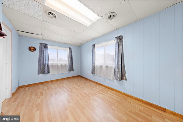 empty room featuring visible vents, a drop ceiling, and wood finished floors