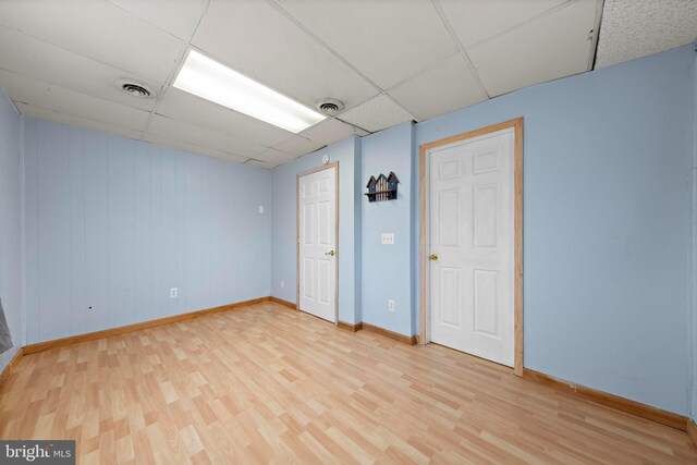 unfurnished room with visible vents, baseboards, a drop ceiling, and light wood-style floors