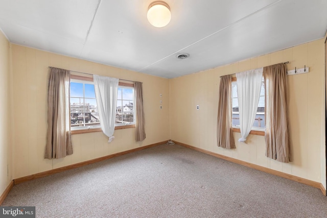 carpeted empty room featuring baseboards and visible vents