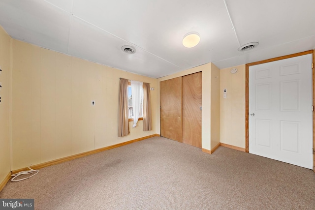 spare room with wood walls, baseboards, carpet, and visible vents