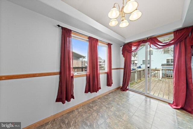 unfurnished dining area with an inviting chandelier and baseboards