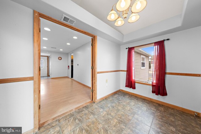 spare room with a notable chandelier, baseboards, recessed lighting, visible vents, and stone finish flooring